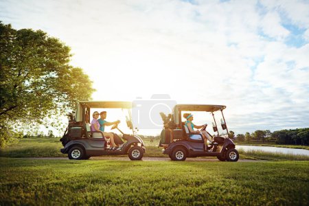 Téléchargez les photos : Quatre fois plus amusant sur ce fairway. un groupe d'amis dans une voiturette de golf sur un terrain de golf - en image libre de droit