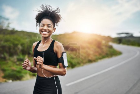 Téléchargez les photos : Exercice, portrait et coureuse heureuse sur une route avec de la musique pour la remise en forme, l'entraînement ou le cardio. Sourire, sport et course féminine africaine dans la nature avec podcast pour l'entraînement, la motivation ou la performance. - en image libre de droit