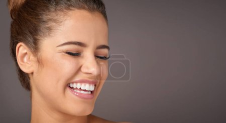 Téléchargez les photos : Moins de maquillage plus de craquement. Plan studio d'une belle jeune femme riant sur un fond gris - en image libre de droit