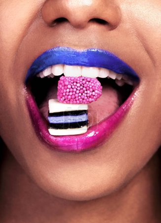 Foto de Los labios atrevidos hablan más alto que las palabras. una mujer irreconocible posando con dulces de regaliz en la boca - Imagen libre de derechos