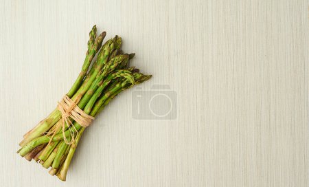 Photo for Delicate, but loaded with nutrients. a bunch of green asparagus tied up with string against a light background - Royalty Free Image
