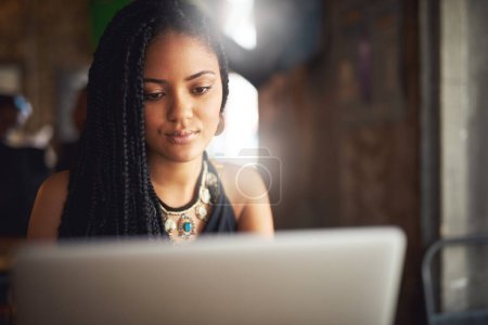 Photo for Adding some new content to her blog. an attractive young woman using her laptop in a coffee shop - Royalty Free Image