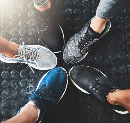 Foto de Sabes que estás ganando cuando llevas zapatos de gimnasia. un grupo de personas de pie juntos en un círculo en el gimnasio - Imagen libre de derechos