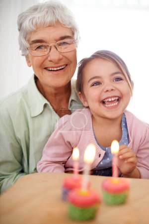Foto de Hoy tengo tres años. Retrato de una abuela feliz celebrando un cumpleaños con su nieta en casa - Imagen libre de derechos