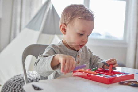 Foto de A los niños les encantan los colores brillantes. un niño jugando con sus crayones en casa - Imagen libre de derechos