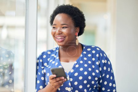 Foto de Es mucho más fácil moverse con tecnología inalámbrica. una joven mujer de negocios usando un smartphone en una oficina moderna - Imagen libre de derechos