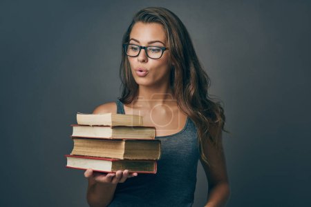 Foto de Nada me excita más que los libros. Foto de estudio de una joven mujer sosteniendo un montón de libros sobre un fondo gris - Imagen libre de derechos