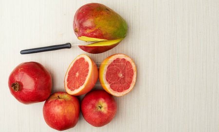 Téléchargez les photos : Prends-toi des fruits juteux. Plan studio d'un pamplemousse coupé en deux, grenade, pommes et mangue sur fond clair - en image libre de droit