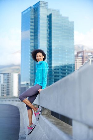 Téléchargez les photos : Je sors un moment de sa course. Portrait d'une jeune joggeuse adossée à une balustrade dans la ville - en image libre de droit