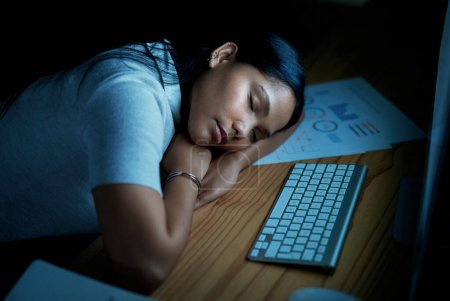 Foto de No tengo nada que dar. joven mujer de negocios durmiendo en su escritorio durante una noche en una oficina moderna - Imagen libre de derechos