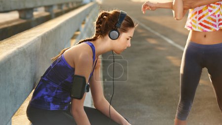 Téléchargez les photos : La musique me donne envie de courir. une jeune joggeuse écoutant de la musique avant une course avec un ami à travers la ville - en image libre de droit