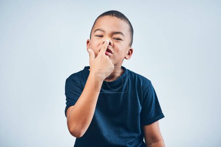 Foto de No puedes obligarme. Estudio de un lindo niño jugando pegando su nariz contra un fondo gris - Imagen libre de derechos