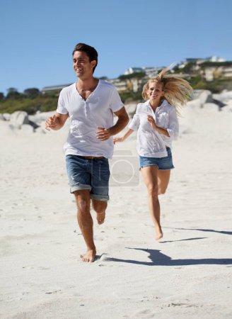 Téléchargez les photos : Je vais courir sur la plage. Un jeune couple courant le long du sable sur la plage - en image libre de droit