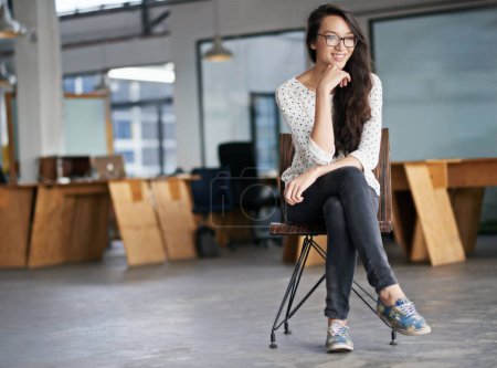 Foto de Siempre está tramando algo. Retrato de una joven atractiva sentada en una oficina - Imagen libre de derechos