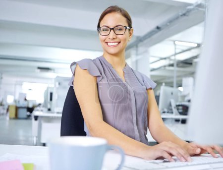 Foto de Me refiero a la eficiencia. una joven y atractiva trabajadora de oficina sentada en su escritorio y trabajando en una computadora - Imagen libre de derechos