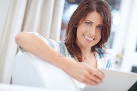 Foto de Navegando a mi propio ritmo. Retrato de una hermosa mujer usando una tableta digital mientras se relaja en el sofá en casa - Imagen libre de derechos