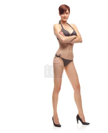 Foto de La confianza suprema es el mejor accesorio. Sexy cabeza roja posando en tacones y un bikini-Studio shot - Imagen libre de derechos