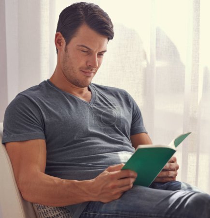 Photo for Getting in some me time. a young man relaxing at home with a book - Royalty Free Image