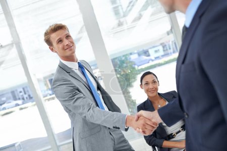 Photo for Business networking. Two businessmen shaking hands in an office lobby - Royalty Free Image
