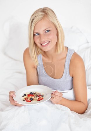 Photo for Breakfast in bed. An attractive young woman eating her breakfast in bed - Royalty Free Image