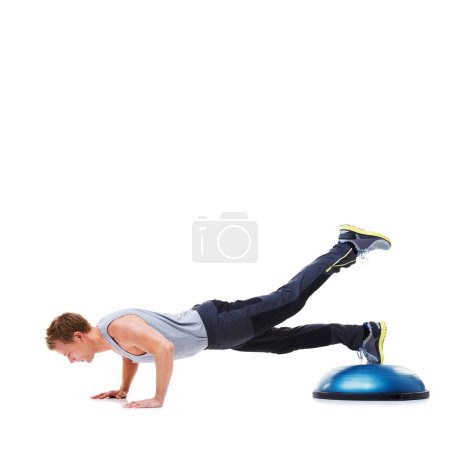 Foto de Él entiende la importancia de un plan de ejercicios sólido. Un joven guapo usando una bola de bosu para un entrenamiento en la parte superior del cuerpo - Imagen libre de derechos