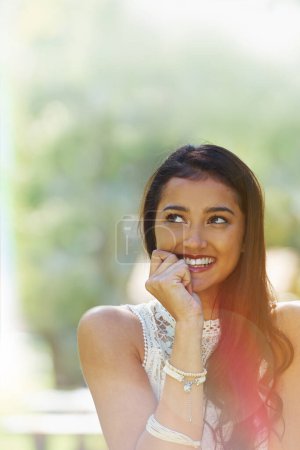 Photo for Shyly smiling. A young woman smiling and looking sideways while standing outside - Royalty Free Image