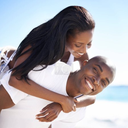 Foto de Disfrutar de las vacaciones contigo es increíble. Un hombre afroamericano guapo dando a su novia una vuelta a cuestas en la playa - Imagen libre de derechos
