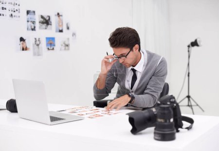 Photo for Finding the right image for his project. a young photographer sitting at his desk editing images - Royalty Free Image