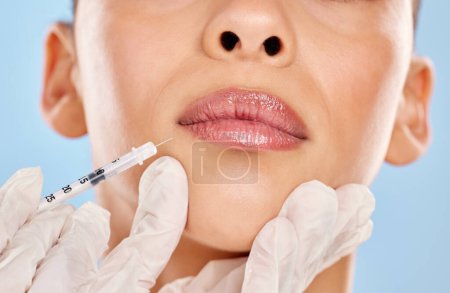 Photo for Plump lips, here I come. Studio portrait of an unrecognisable woman receiving a botox injection against a blue background - Royalty Free Image