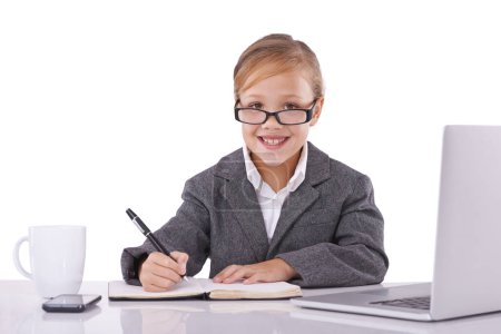 Foto de Esta niña está creciendo en la palabra corporativa. Una niña vistiendo un traje y escribiendo en su libro - Imagen libre de derechos