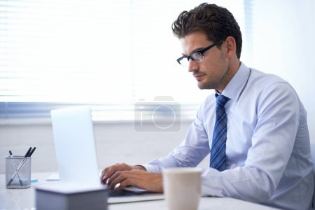 Foto de Poner en el trabajo y el éxito seguirá. un joven hombre de negocios guapo trabajando en una computadora portátil - Imagen libre de derechos