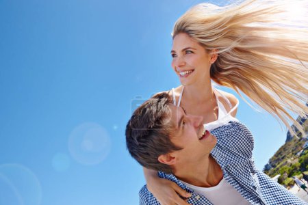 Téléchargez les photos : Sentez l'air marin dans vos cheveux. un jeune couple heureux profitant d'une balade à dos de cochon à la plage - en image libre de droit