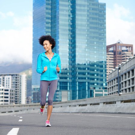 Photo for Tearing up the road. a young woman jogging alone through empty city streets - Royalty Free Image