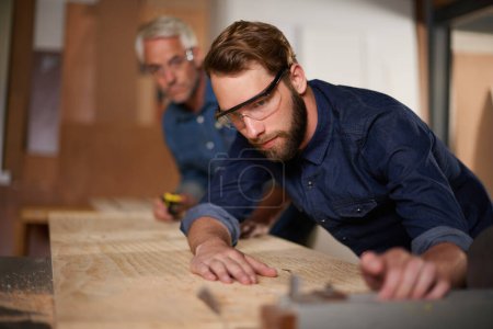 Foto de Aprendiendo el oficio. un padre y un hijo trabajando juntos en un proyecto de carpintería en un taller - Imagen libre de derechos