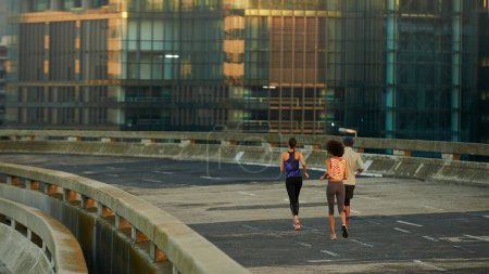 Foto de Esta mañana las calles son nuestras. Vista trasera de tres jóvenes corredores corriendo por una calle vacía al amanecer - Imagen libre de derechos
