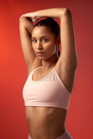 Photo for Wake up, workout and win that glow. Studio portrait of a sporty young woman stretching her arms against a red background - Royalty Free Image