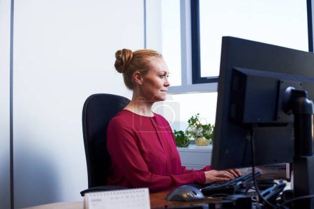 Foto de Mecanografiando. una atractiva mujer de negocios usando su computadora de trabajo - Imagen libre de derechos