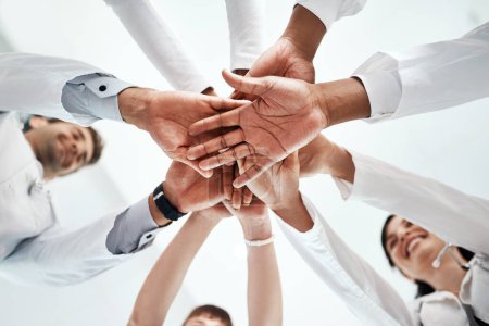 Photo for We promise to put our patients first. Low angle shot of a diverse team of doctors joining their hands together in a hospital - Royalty Free Image