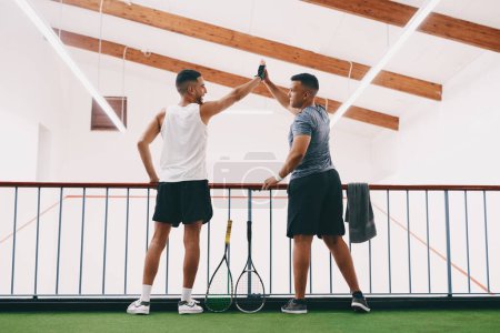Photo for Teamwork makes a winner out of everyone. Rearview shot of two young men celebrating while watching a game of squash from the viewing gallery - Royalty Free Image