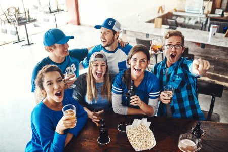 Téléchargez les photos : Son jour de jeu Tête vers le bas et le soutien. un groupe d'amis buvant des bières en regardant un match de sport dans un bar - en image libre de droit
