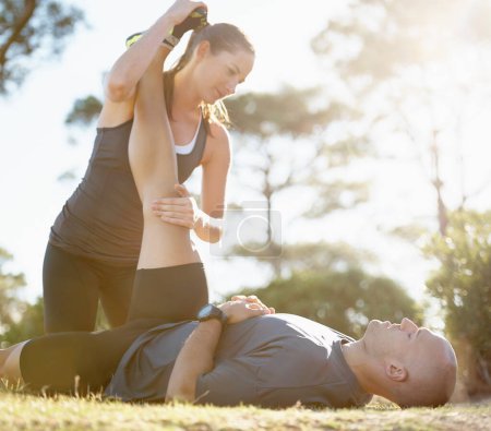 Photo for Let me help you stretch. A young woman helping her boyfriend stretch after a run - Royalty Free Image