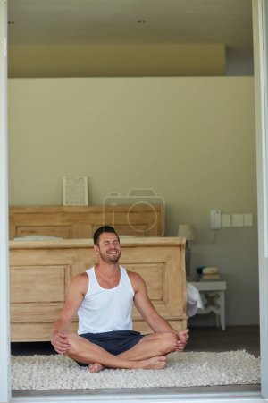 Téléchargez les photos : La méditation le calme le matin. un jeune homme beau pratiquant le yoga à la maison - en image libre de droit