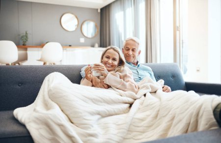 Photo for Under the blankets where its warm and cosy. a mature couple relaxing on the sofa at home - Royalty Free Image