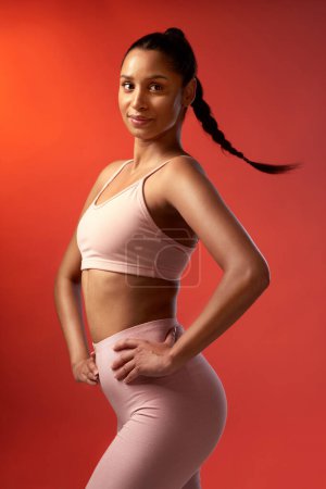 Photo for Strong, slim and totally confident. Studio shot of a sporty young woman posing against a red background - Royalty Free Image