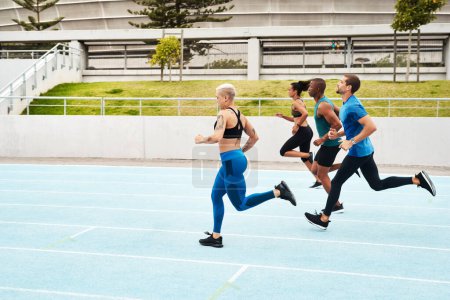 Photo for Keep calm and get fit. Full length shot of a diverse group of athletes racing each other during an outdoor track and field workout session - Royalty Free Image