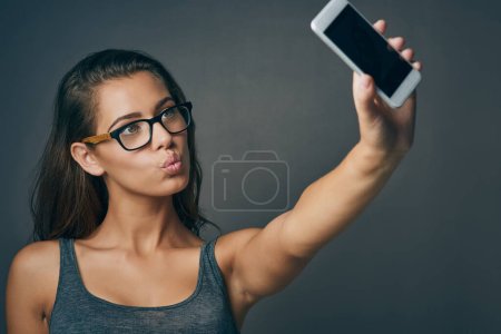 Photo for May your day be as flawless as your selfies. Studio shot of an attractive young woman taking a selfie against a grey background - Royalty Free Image