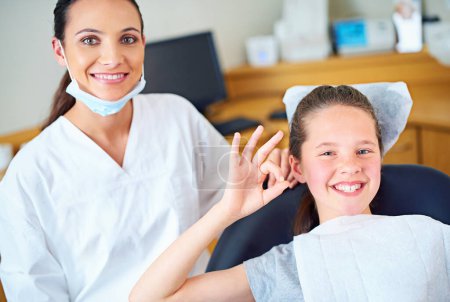 Photo for Perfect checkup every time. Portrait of a young girl sitting in a dentists chair giving an ok sign - Royalty Free Image