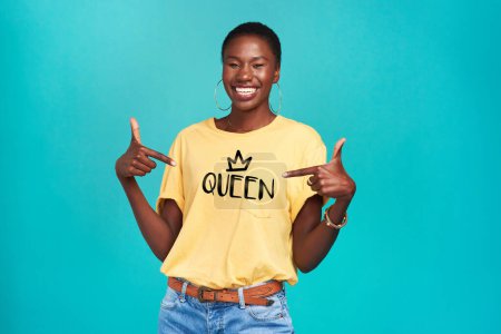 Photo for Queen, print and tshirt on a black woman for equality and human rights isolated in a blue background studio. Fashion, fearless and African gen z or female person happy with quotes in her clothes. - Royalty Free Image
