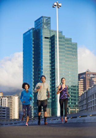 Téléchargez les photos : Mettre des kilomètres sous nos pieds. trois jeunes joggeurs sortent courir dans les rues de la ville - en image libre de droit