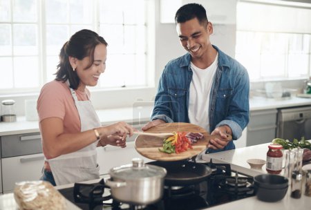 Foto de Aquí, déjame ayudarte. una joven pareja cocinando juntos en casa - Imagen libre de derechos